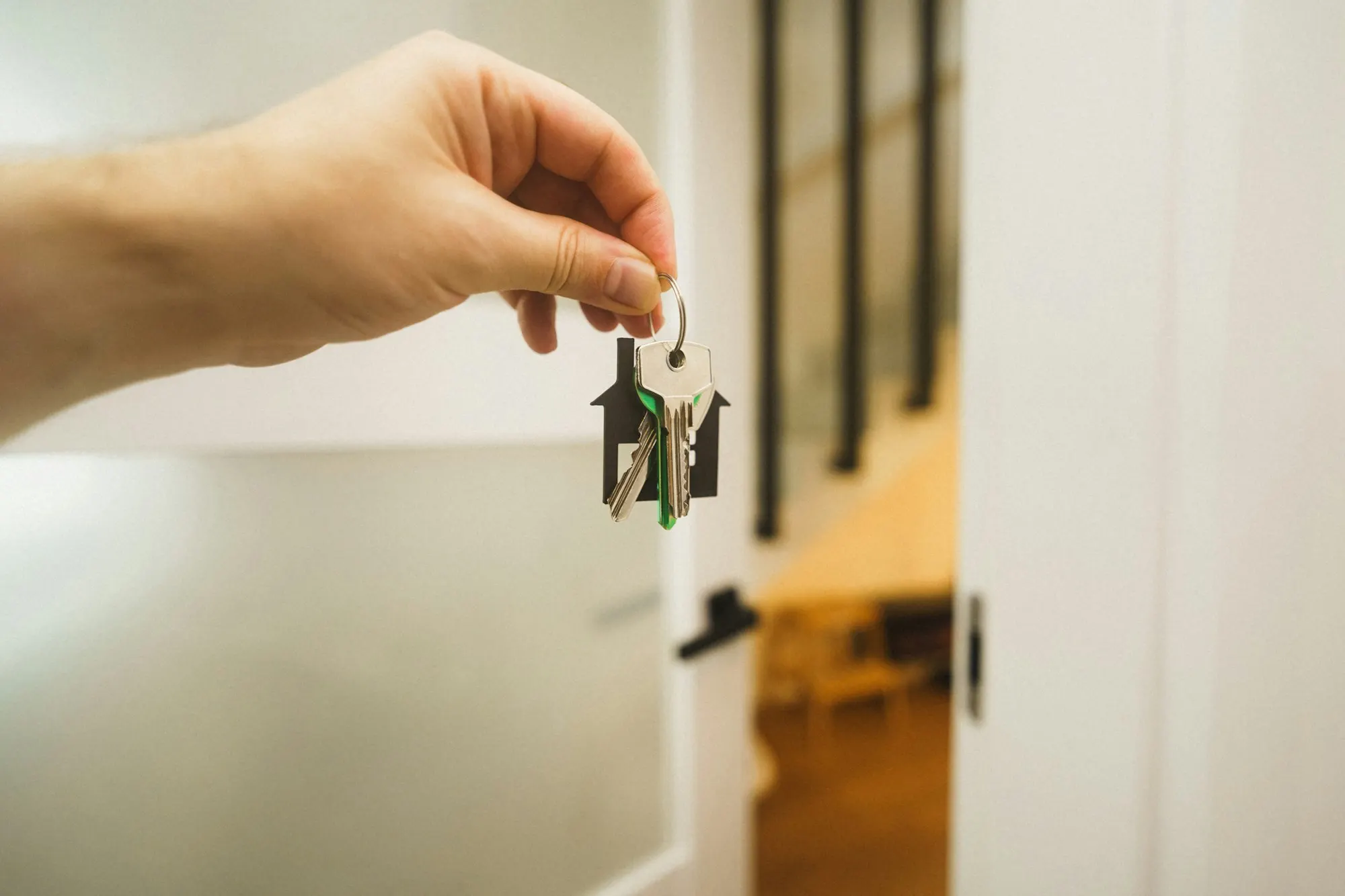 Hand houdt een sleutel voor de open deur van een lichte woning